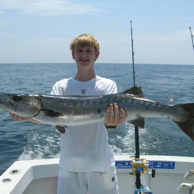 a man holding a fish on a boat in a body of water