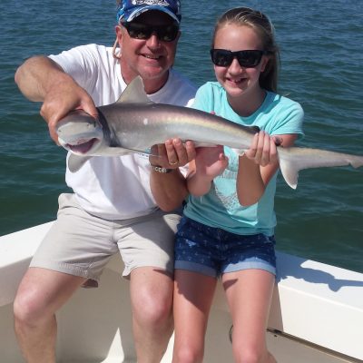 a woman holding a fish on a boat in a body of water
