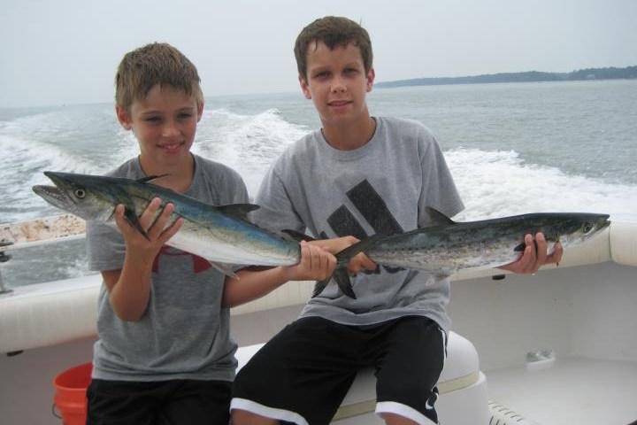 a young boy holding a fish in the water