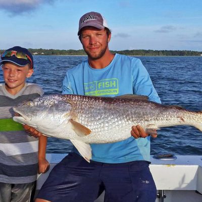 a man holding a fish on a boat in a body of water