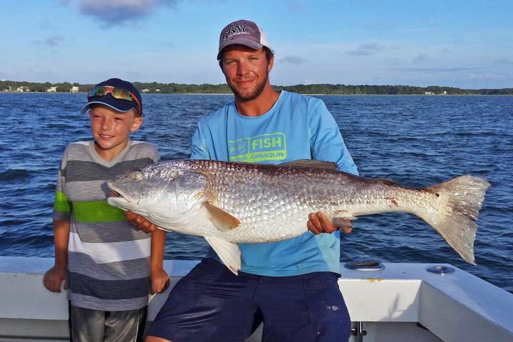 a man holding a fish on a boat in a body of water