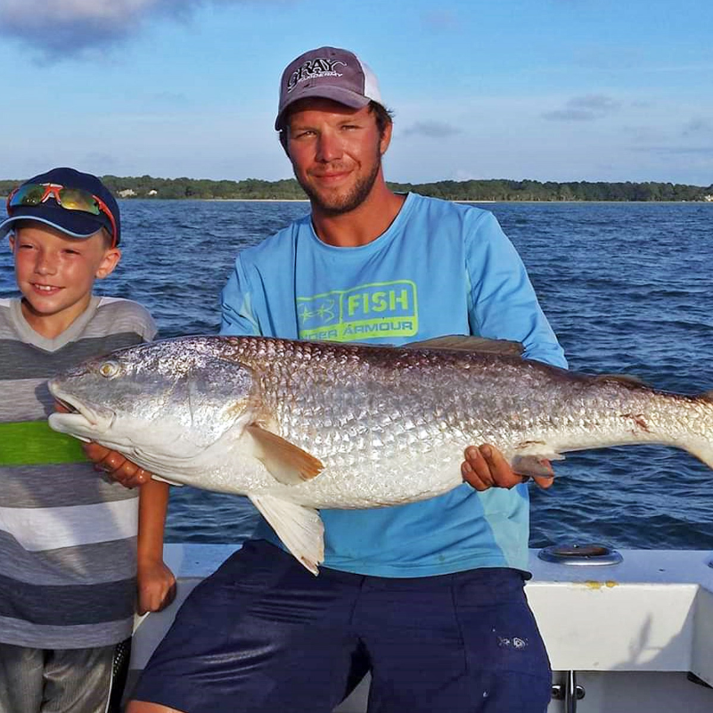 a person holding a fish on a boat in a body of water