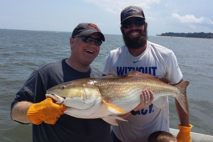 a man holding a fish on a boat in a body of water