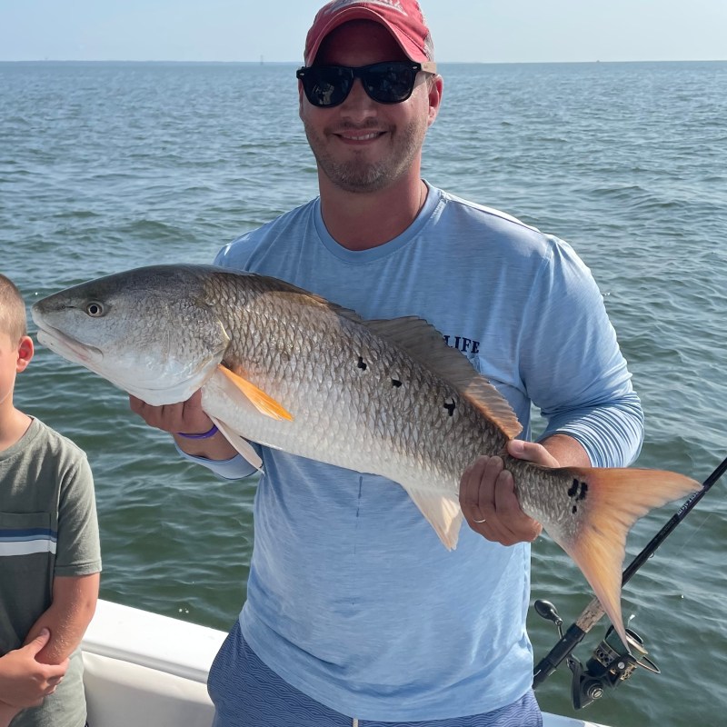 a man holding a redfish in the water